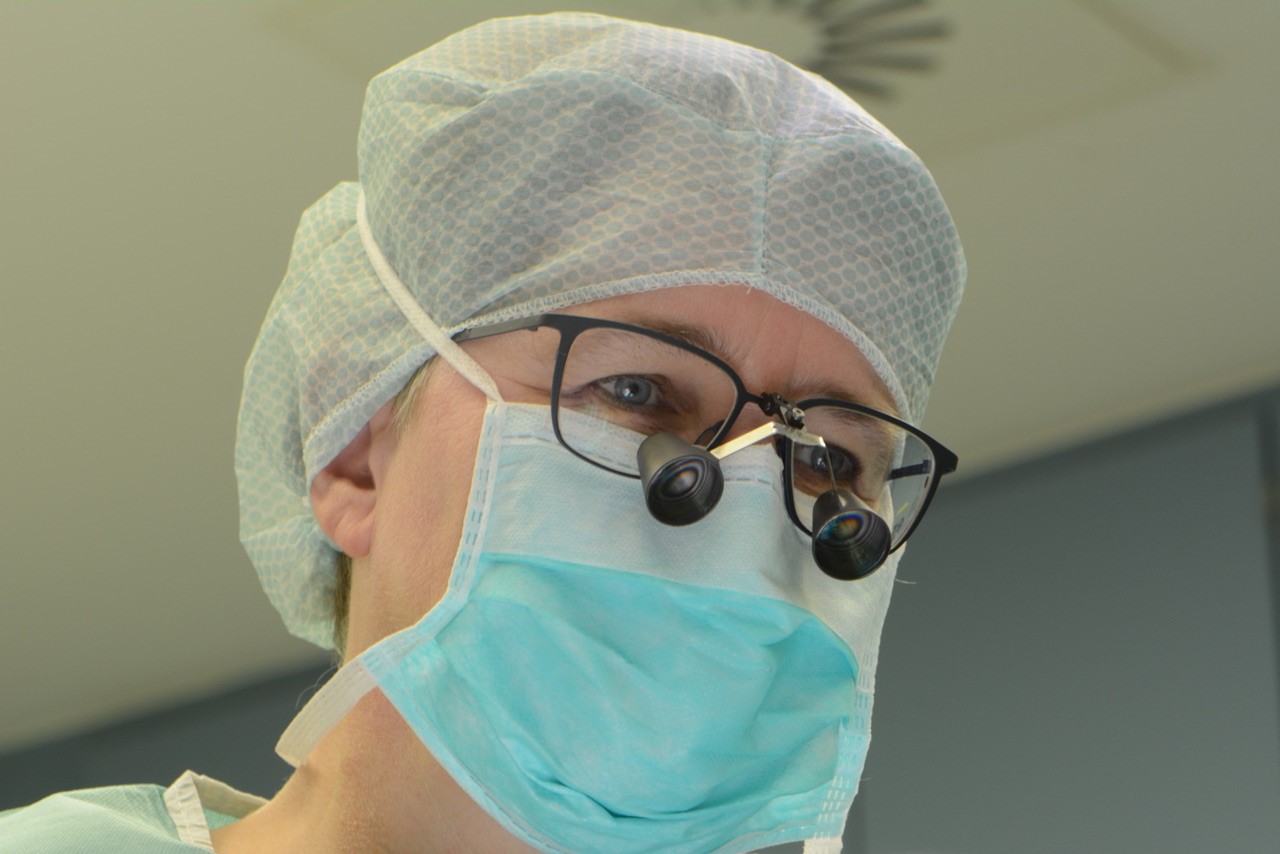 Eine Chirurgin im OP mit Lupen vor der Brille
