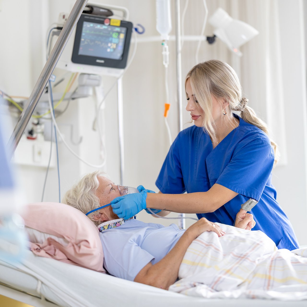 Eine Pflegerin betreuen eine schwer kranke Patientin auf der Intensivstation, sie bekommt eine Sauerstoffmaske angelegt