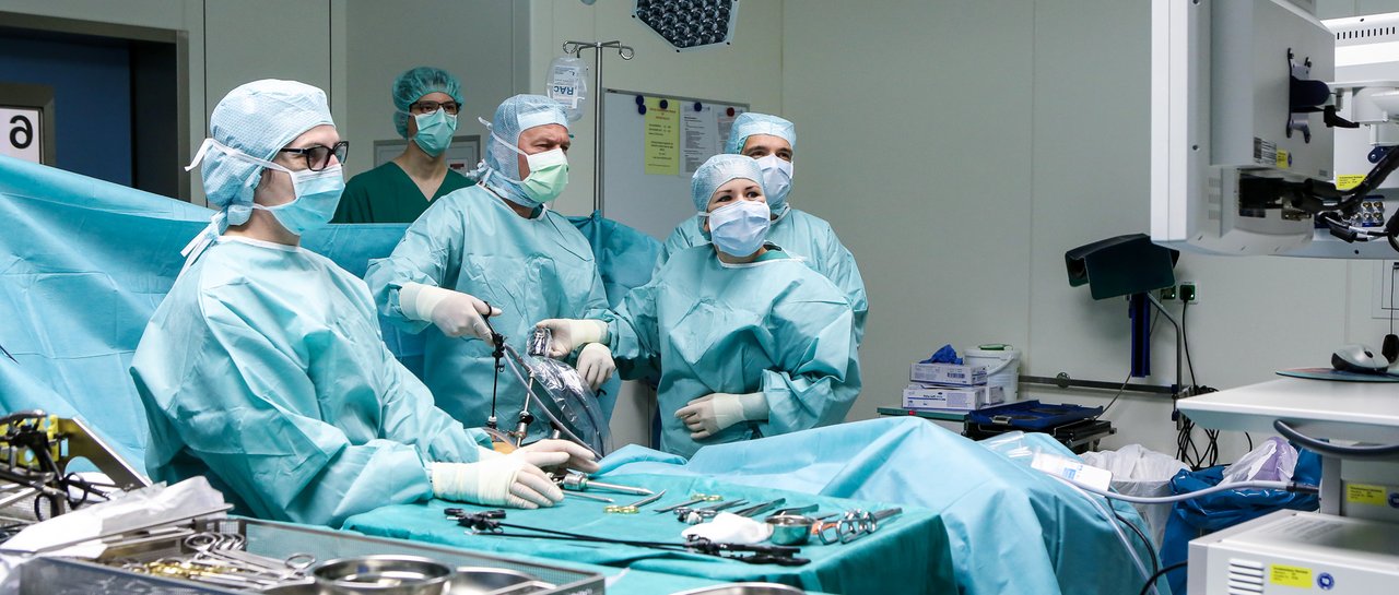 Ein Ärzteteam operiert einen Bauch, es werden Instrumente gehalten und konzentriert auf einen Bildschirm geschaut