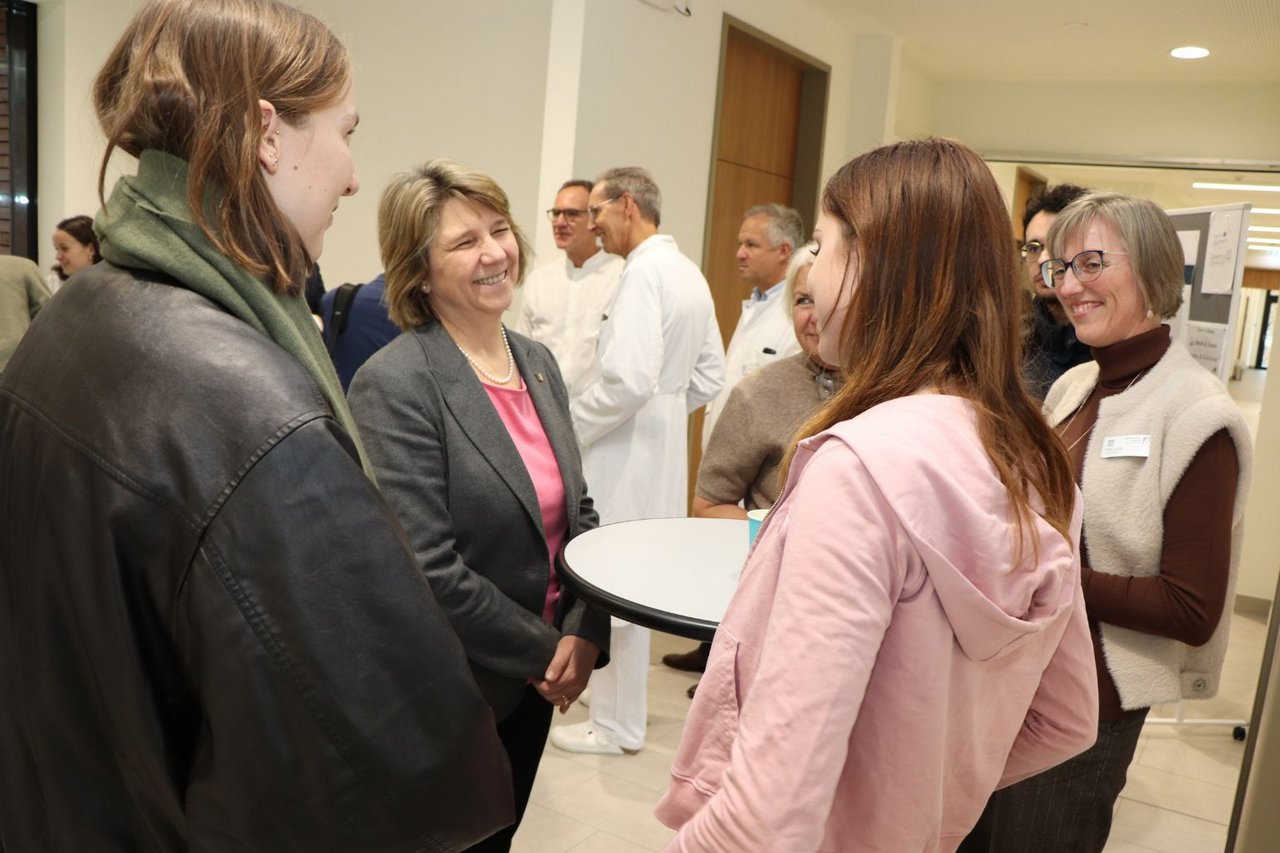 Gesundheitsministerin Kerstin von der Decken steht im Flur des Campuses und unterhält sich mit Auszubildenden. 
