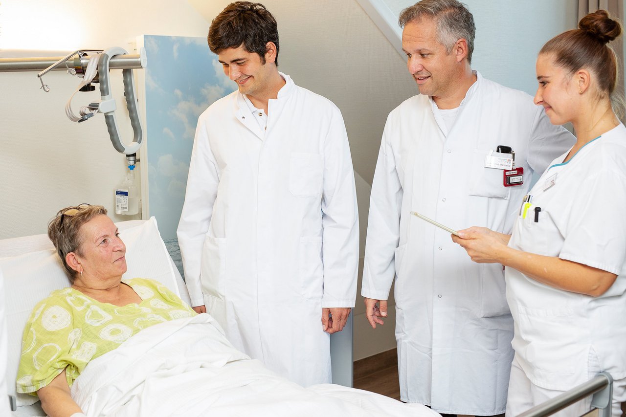 2 Ärzte und eine Pflegerin in einer Visite im Patientenzimmer