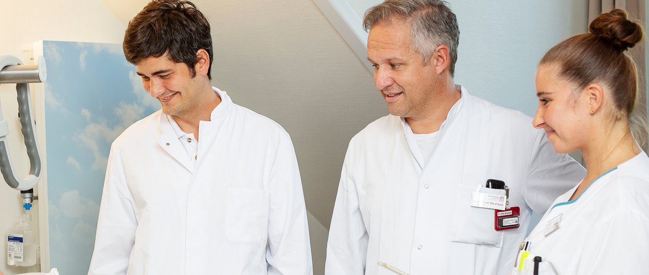 2 Ärzte und eine Pflegerin in einer Visite im Patientenzimmer
