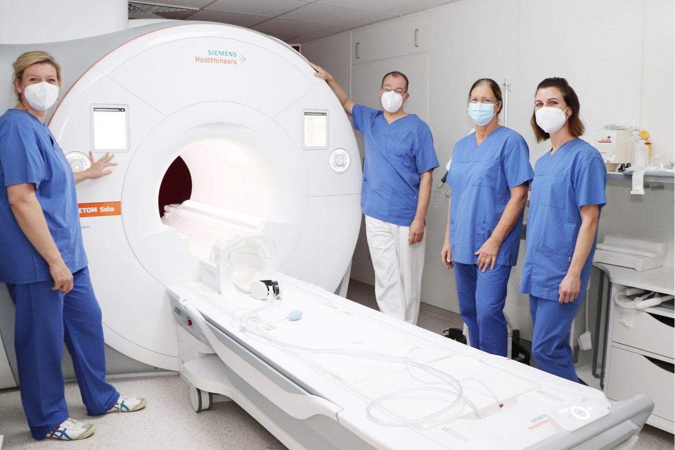 Team der Radiologie steht gemeinsam neben einem neuen Magnetresonanztomografen (MRT).