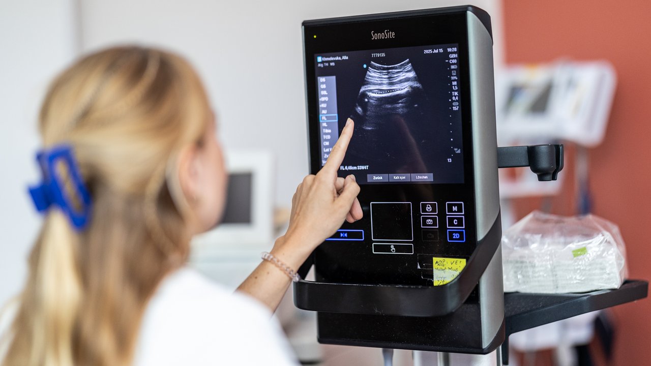 Eine Ärztin führt einen Ultraschall an einer Schwangeren durch und betrachtet den Bildschirm