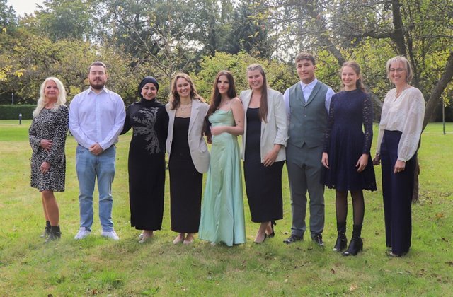 Gruppe von Auszubildenden und zwei Begleitpersonen steht gemeinsam auf einer Wiese im Freien und posiert für ein Gruppenfoto.