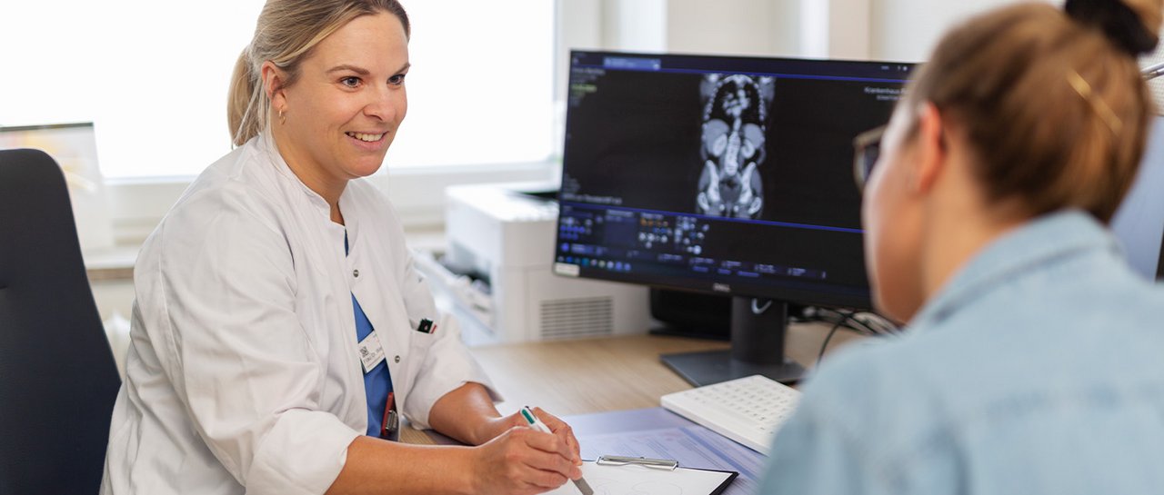 Eine Ärztin spricht freundlich mit einer Patientin und erläutert etwas