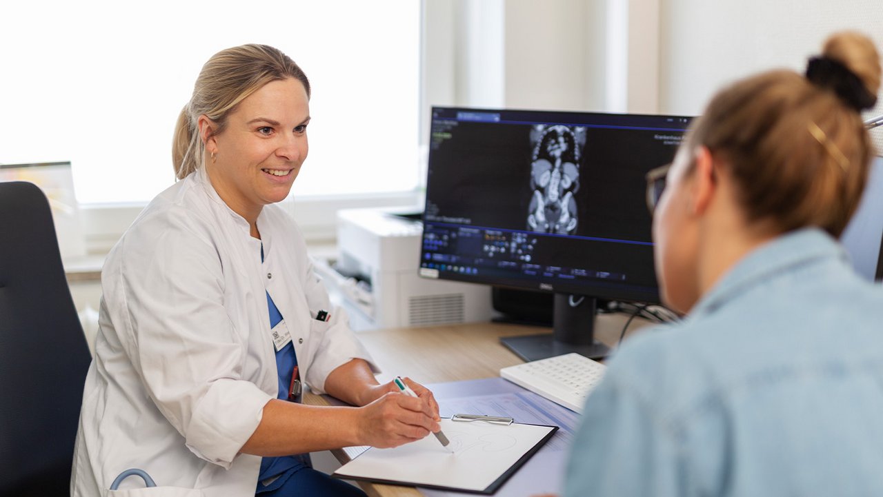 Eine Ärztin spricht freundlich mit einer Patientin und erläutert etwas