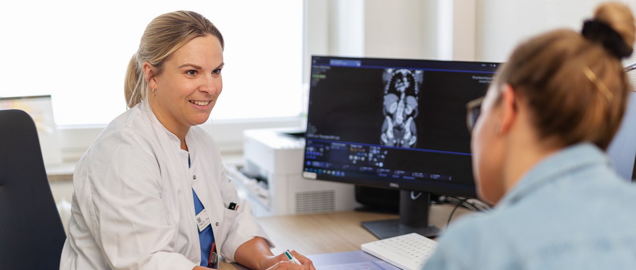 Eine Ärztin spricht freundlich mit einer Patientin und erläutert etwas