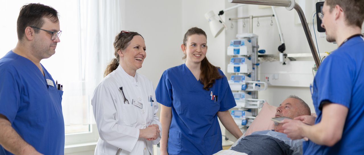 Ärzte und Pflegekräfte stehen um ein Patientenbett herum