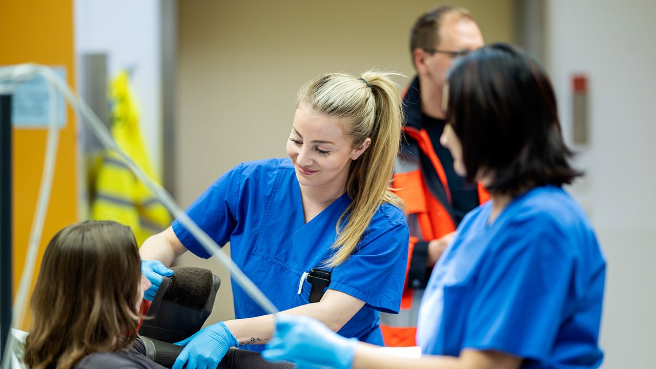 Zwei Pflegerinnen in der ZNA behandeln eine Patientin und messen Blutdruck