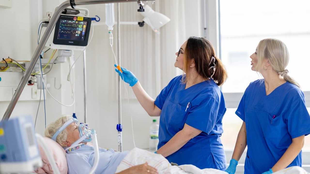 2 Pflegerinnen betreuen eine schwer kranke Patientin auf der Intensivstation