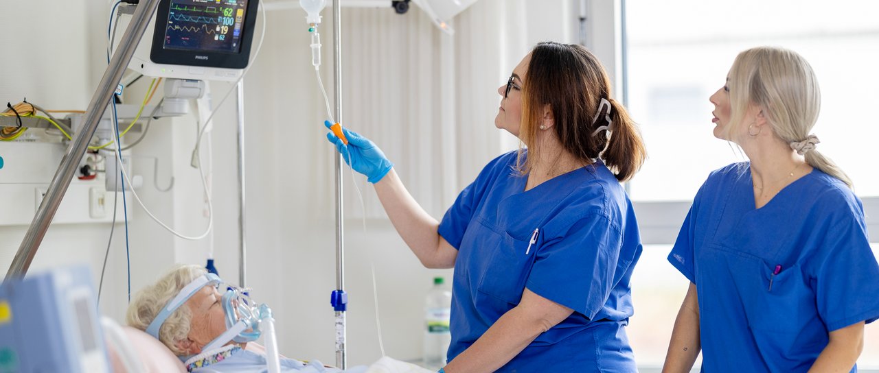 2 Pflegerinnen betreuen eine schwer kranke Patientin auf der Intensivstation