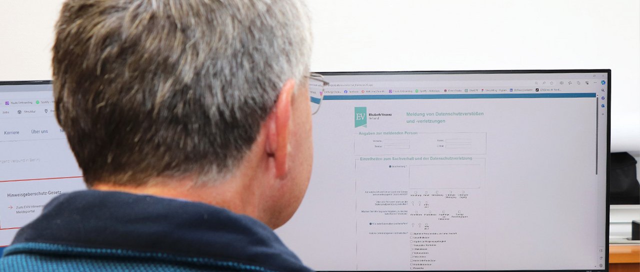 Ein Mann schaut auf einen Computerbildschirm auf dem das Meldeportal zu sehen ist