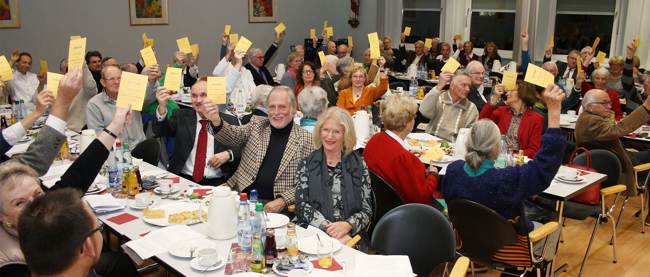 Die Mitglieder des Fördervereins halten Zettel hoch zur Abstimmung. Es sind um die 50 Menschen bei der Versammlung.