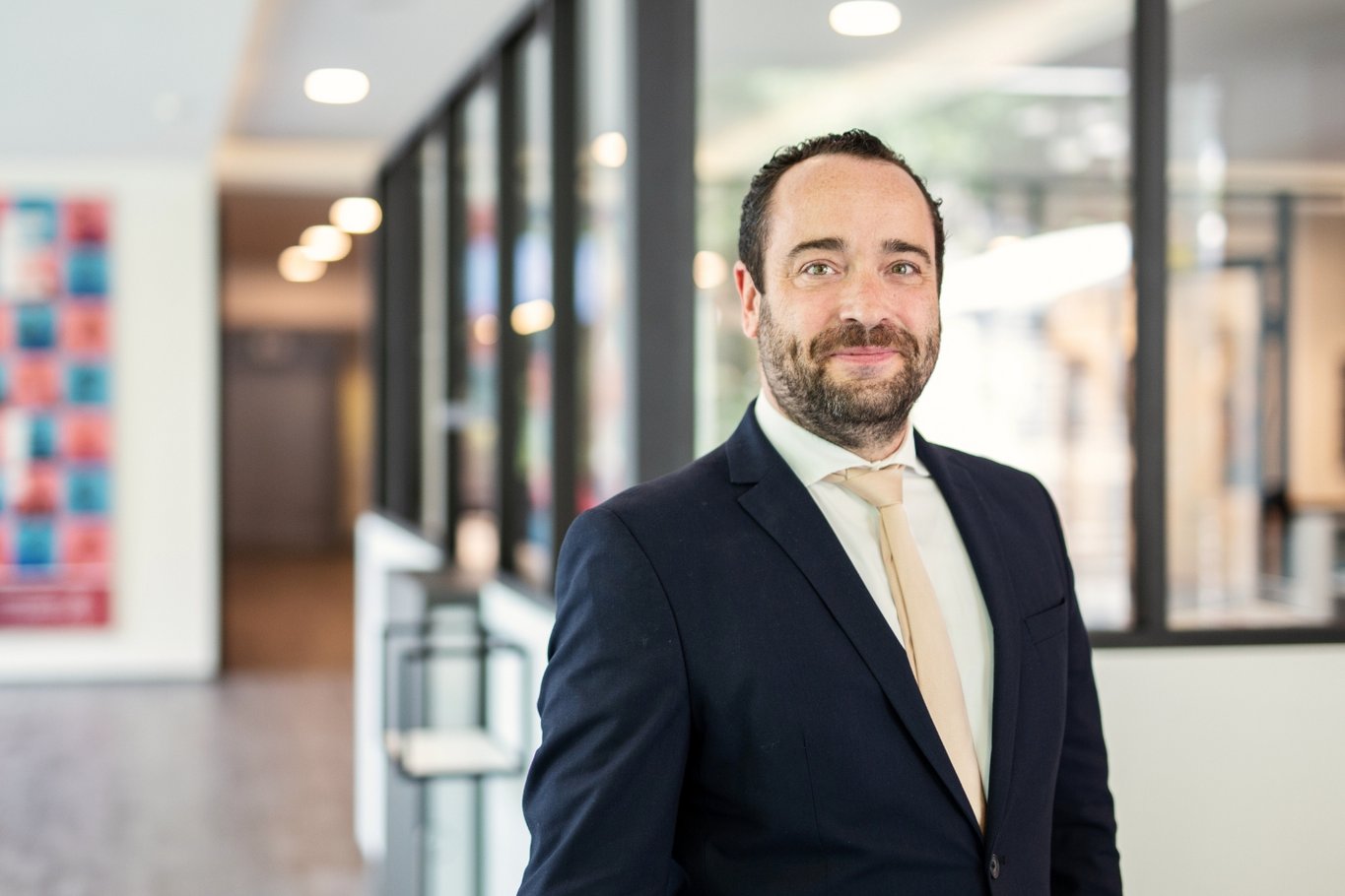 Moritz Kurzmann steht in einem Anzug in einem hellen Flur des Krankenhaus Reinbek und lächelt in die Kamera.