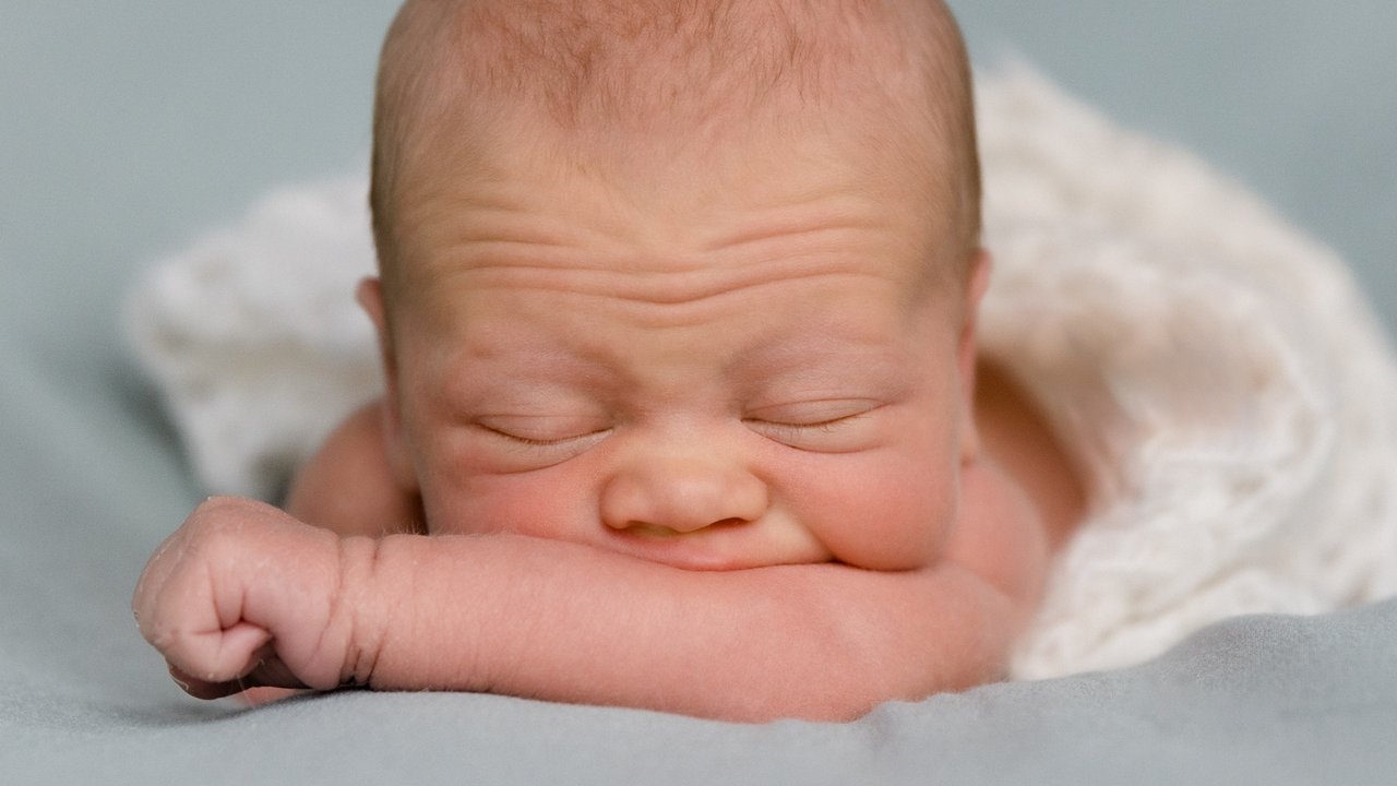 Stockbild eines Babys, das auf seinem Arm liegt