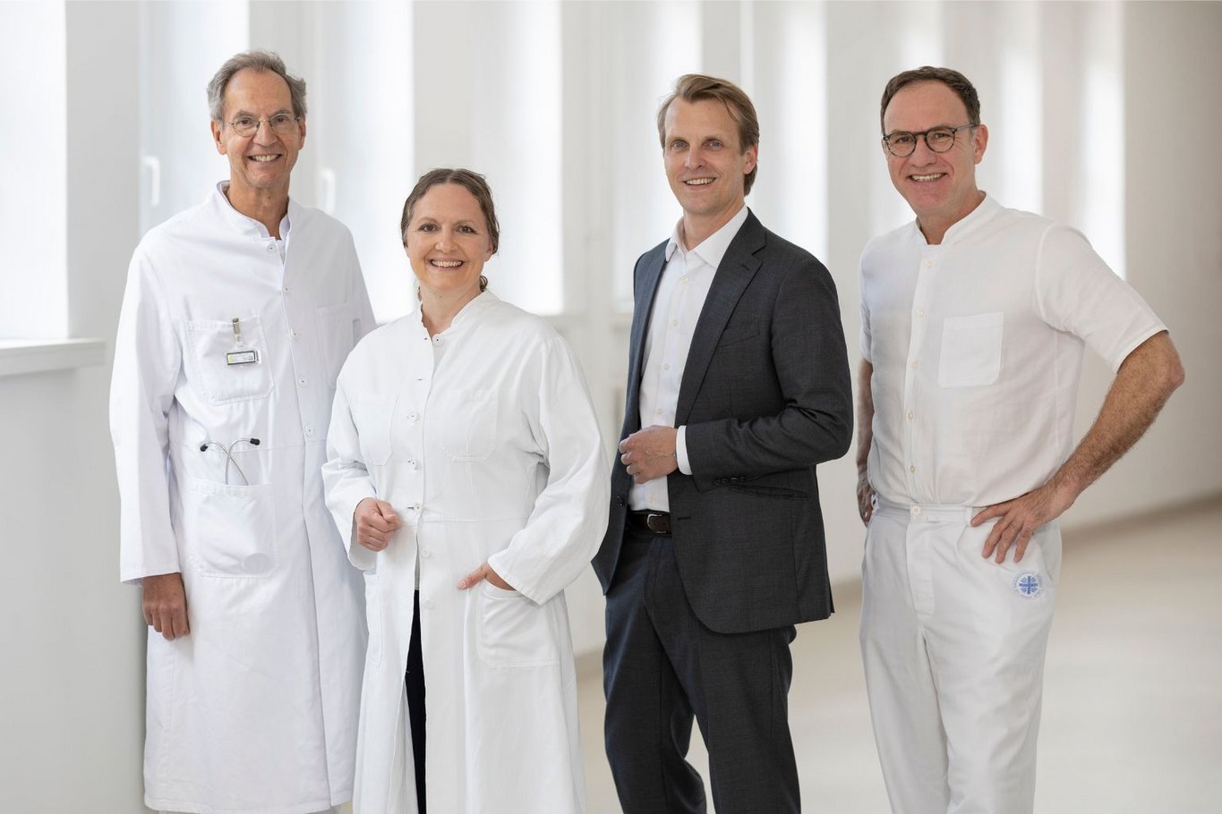 Vier Mitglieder der Krankenhausleitung stehen gemeinsam im Flur des Krankenhauses Reinbek, drei in Arztkitteln und eine Person im Anzug.