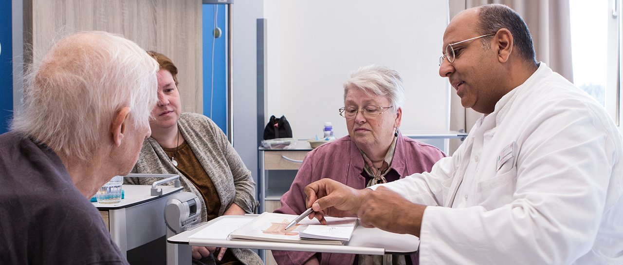 Ein Arzt erklärt einem Patienten und seinen Angehörigen den Vorgang einer OP