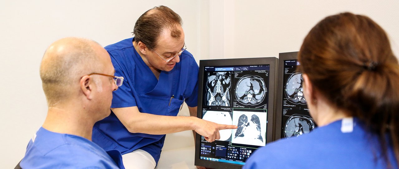 3 Radiologen schauen sich ein Bild auf dem Bildschirm an und diskutieren