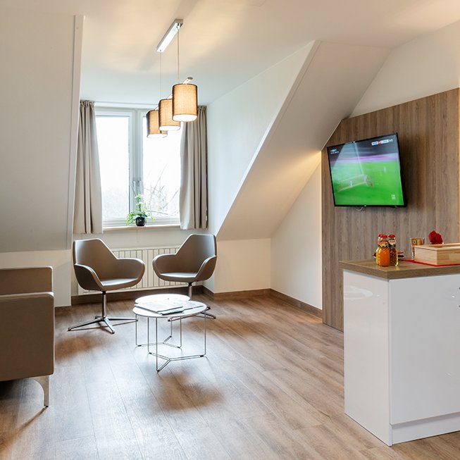 Die Lounge eines privaten Patientenzimmers. Der Raum ist geräumig und hell ausgeleuchtet