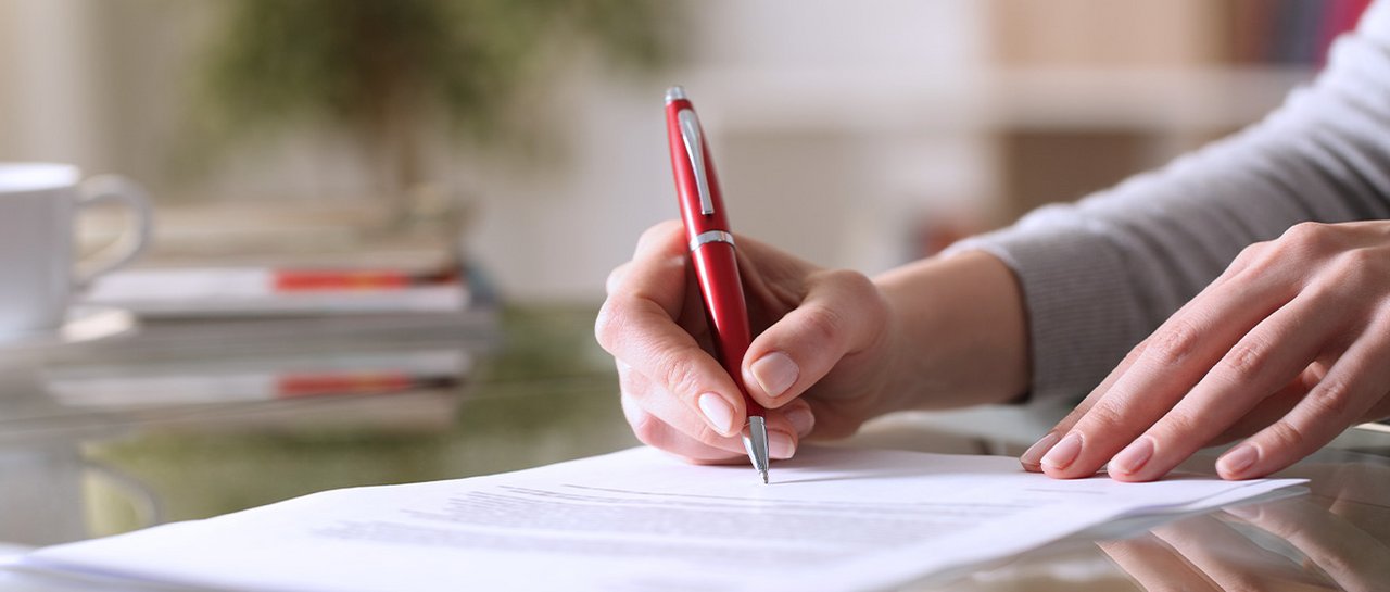 Stockbild einer Hand die ein Papier unterschreibt