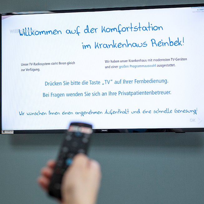Ein Fernseher der grade mit einer Fernbedienung angeschaltet wird 