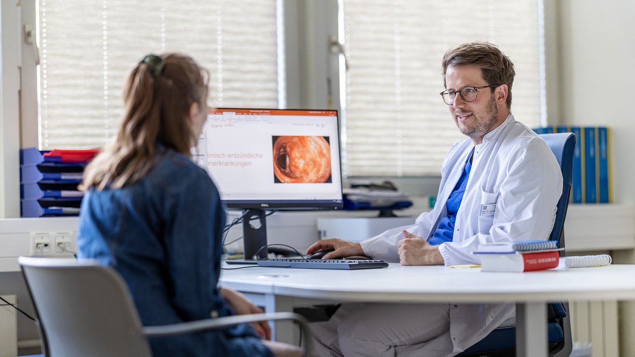 Eine Patientin spricht mit dem Arzt in einer Sprechstunde, während der Arzt etwas auf dem Computerbildschirm zeigt