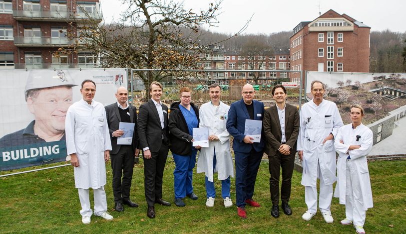 Alle freuen sich über die vier Förderbescheide vor der Baustelle des Notfallzentrums Alle freuen sich über die vier Förderbescheide vor der Baustelle des Notfallzentrums