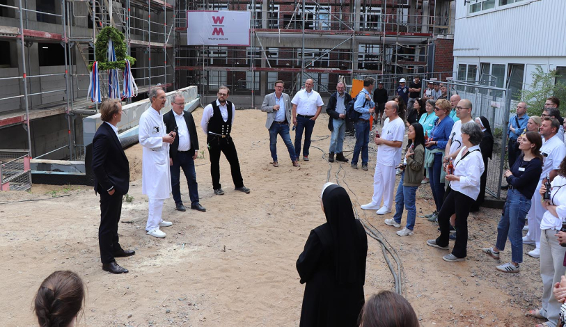 Einige der Gäste des Richtfest stehen neben der Baustelle