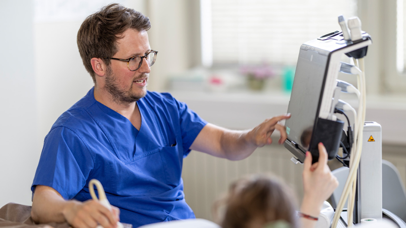 Dr. Schneider zeigt Patientin etwas auf dem Ultraschall Bildschirm