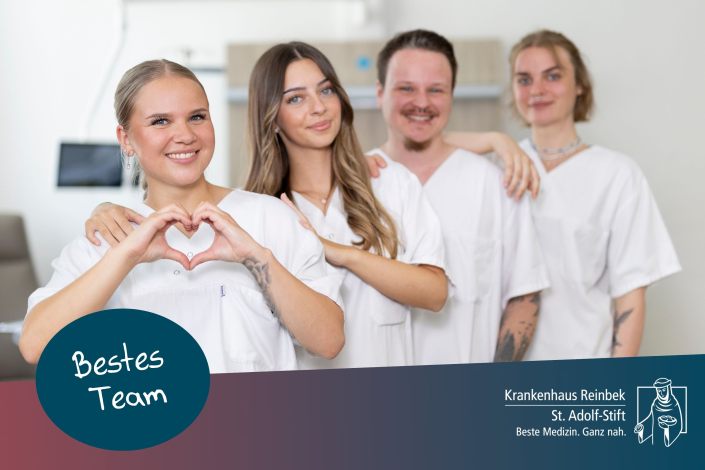 Vier Pflegekräfte lächeln in die Kamera, die Pflegerin links formt ein Herz mit ihren Händen