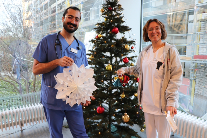 Mitarbeitende präsentieren ihre Geschenke vor dem Weihnachtsbaum im Foyer