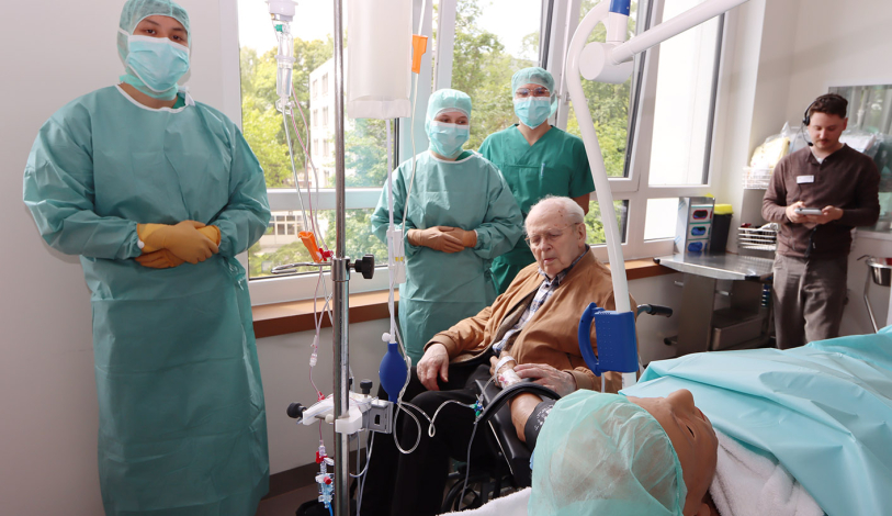 OTA-Azubis zeigen dem Spender die Patientenpuppe, er nimmt den Puls