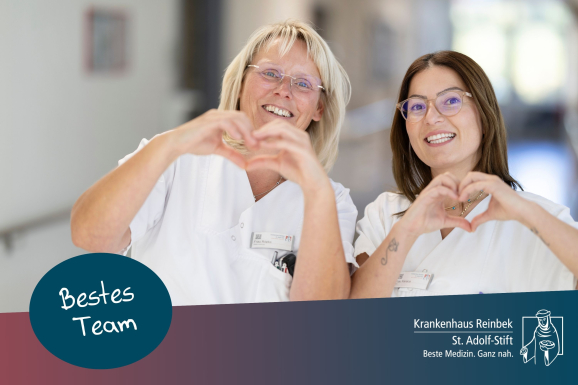 Zwei Pflegerinnen lachen und formen ein Herz mit ihren Händen