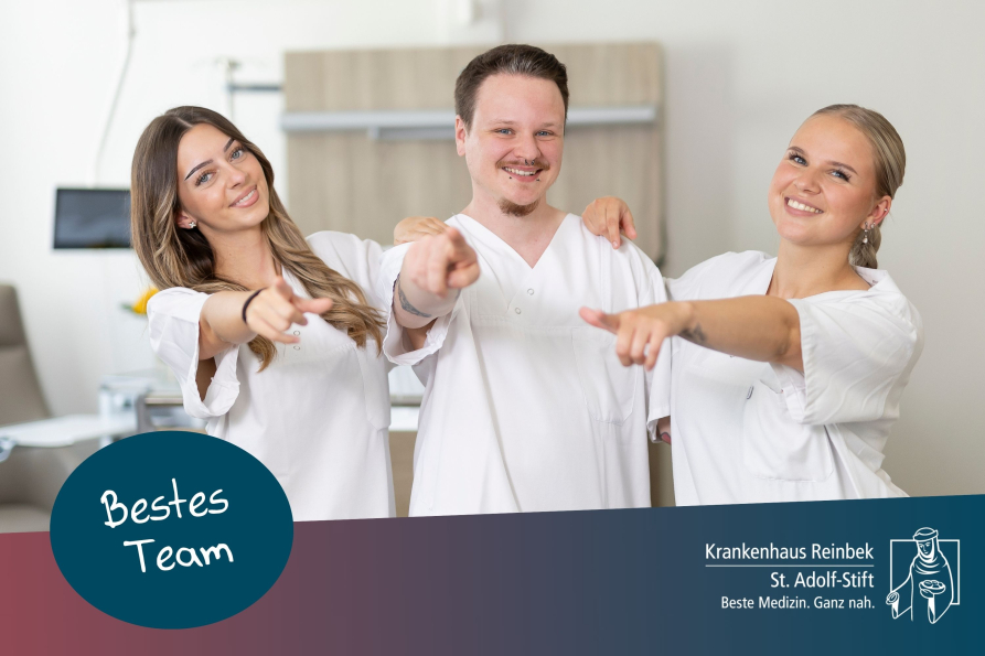 Drei Pflegekräfte zeigen mit dem Finger zur Kamera und lächeln