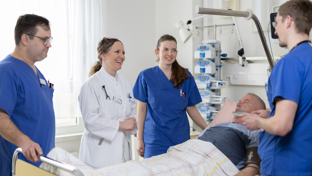 Ärzte und Pflegekräfte stehen um ein Patientenbett herum