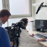 Dr Annette Sommerfeld im Untersuchungsraum mit Patienten und TV Team