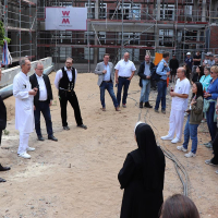 Einige der Gäste des Richtfest stehen neben der Baustelle