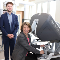 Bei einem Rundgang durch den Neubau erklärte OTA-Auszubildende Maximilian Weise der Gesundheitsministerin Kerstin von der Decken einen Operationsroboter, der eigens für die Veranstaltung im Campus aufgestellt wurde. Er lud sie ein sich an die Steuerkonsole zu setzen, um selbst zu erfahren, wie intuitiv die Arme zu bedienen sind. Ein baugleicher OP-Roboter steht nur 100 Meter weiter im Zentral-OP des St. Adolf-Stiftes.