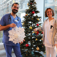 Mitarbeitende präsentieren ihre Geschenke vor dem Weihnachtsbaum im Foyer
