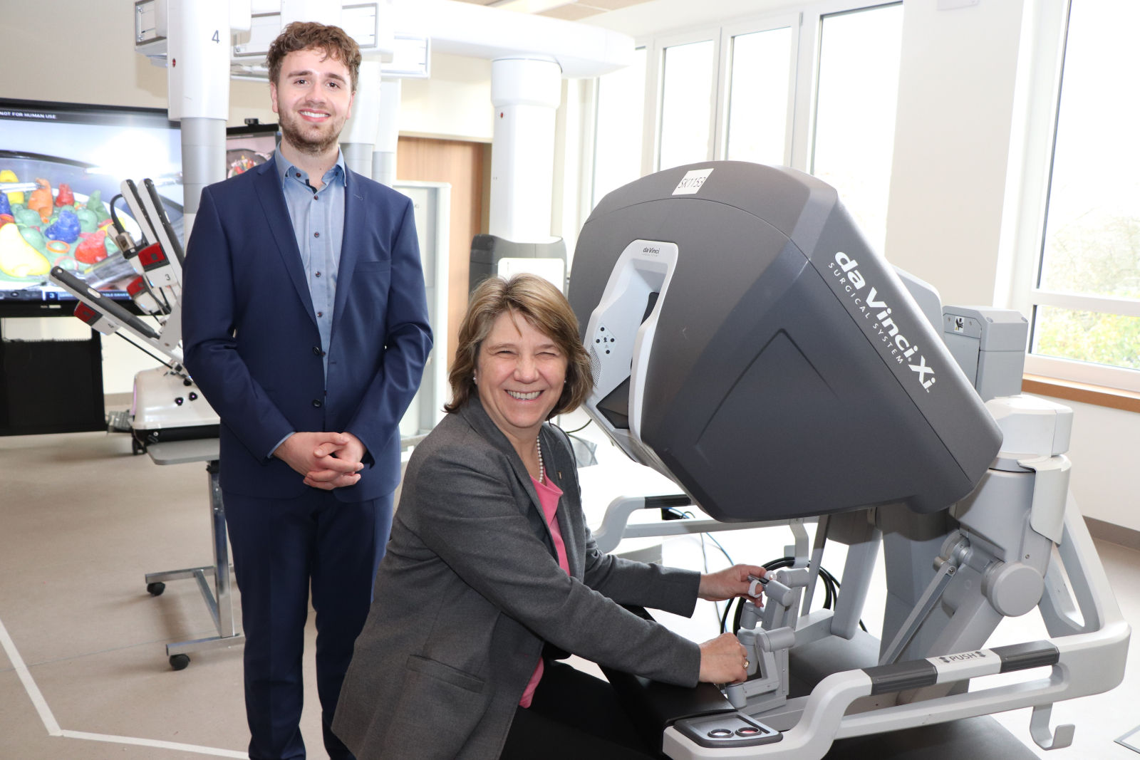 Bei einem Rundgang durch den Neubau erklärte OTA-Auszubildende Maximilian Weise der Gesundheitsministerin Kerstin von der Decken einen Operationsroboter, der eigens für die Veranstaltung im Campus aufgestellt wurde. Er lud sie ein sich an die Steuerkonsole zu setzen, um selbst zu erfahren, wie intuitiv die Arme zu bedienen sind. Ein baugleicher OP-Roboter steht nur 100 Meter weiter im Zentral-OP des St. Adolf-Stiftes.