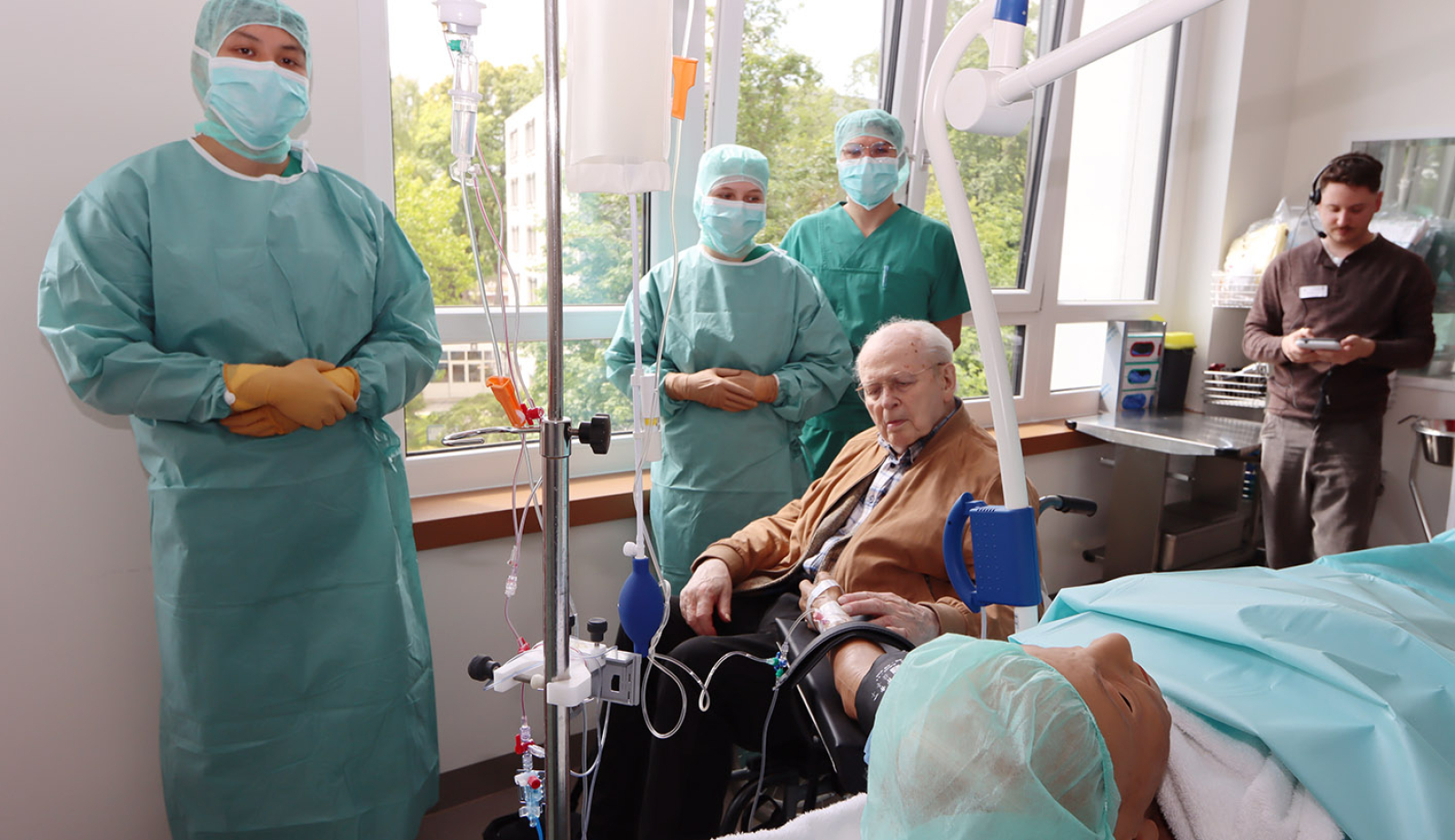 OTA-Azubis zeigen dem Spender die Patientenpuppe, er nimmt den Puls