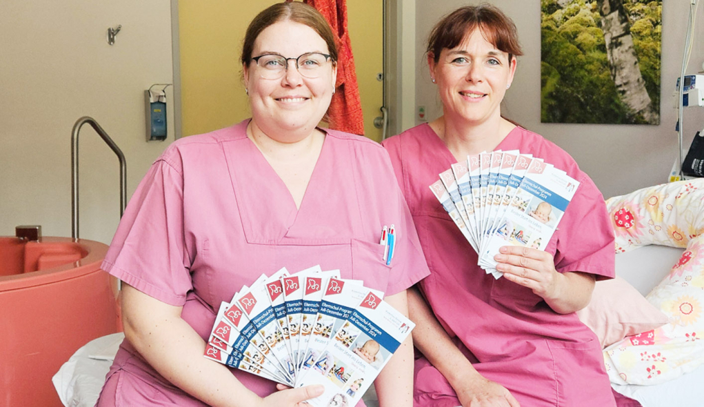 die neuen Elternschulflyer sind da Zwei Mitarbeiterinnnen der Geburtshilfe zeigen die neuen Elternschulflyer