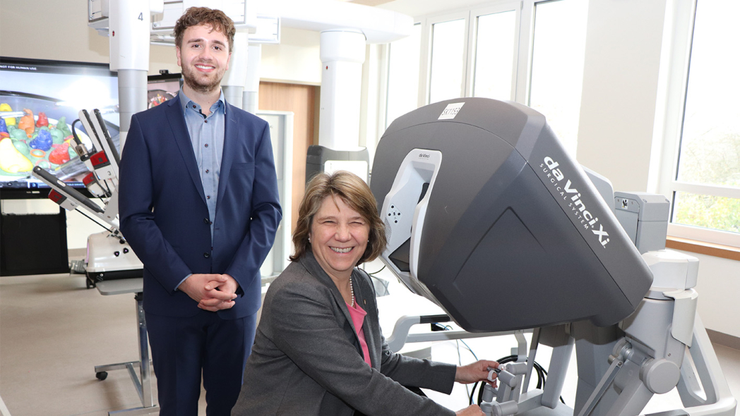 Bei einem Rundgang durch den Neubau erklärte OTA-Auszubildende Maximilian Weise der Gesundheitsministerin Kerstin von der Decken einen Operationsroboter, der eigens für die Veranstaltung im Campus aufgestellt wurde. Er lud sie ein sich an die Steuerkonsole zu setzen, um selbst zu erfahren, wie intuitiv die Arme zu bedienen sind. Ein baugleicher OP-Roboter steht nur 100 Meter weiter im Zentral-OP des St. Adolf