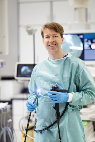 Ehlken hält ein Endoskop hoch und guckt in die Kamera