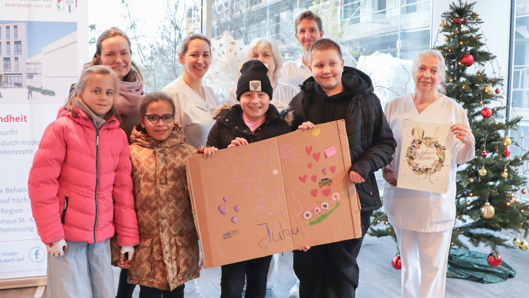 Kinder der Klasse 4c der Klosterbergenschule übergeben gemeinsam mit ihrer Lehrerin Geschenke an Krankenhausmitarbeitende des St. Adolf-Stifts.