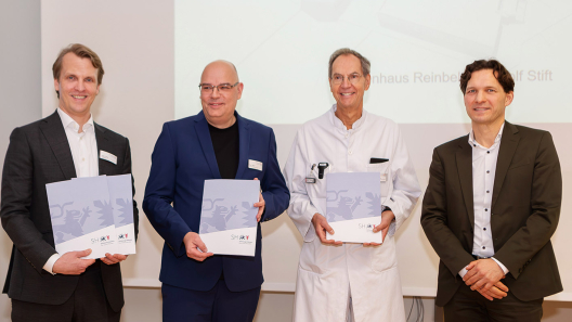 Das Krankenhausdirektorium hält die 4 Förderbescheide, die Gesundheits-Staatssekretär Dr. Oliver Grundei (r.) im Namen des Gesundheitsministeriums für die großen Bauprojekte des St. Adolf-Stiftes überreicht hat, stolz in den Händen: Krankenhaus-Geschäftsführer Fabian Linke (li.), Pflegedirektor Nils-Michael Wulf und der Ärztliche Direktor Prof. Stefan Jäckle.