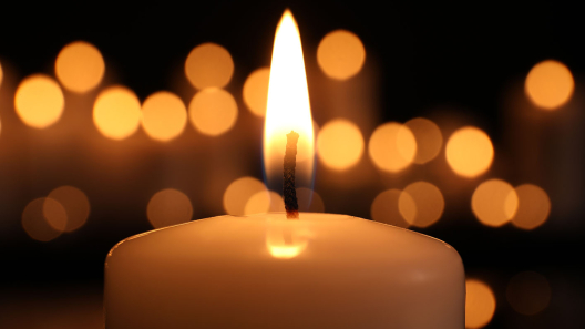 Word Candle Lighting Eine Kerze brennt im Vordergrund und dahinter sind ganz viele Kerzenlichter