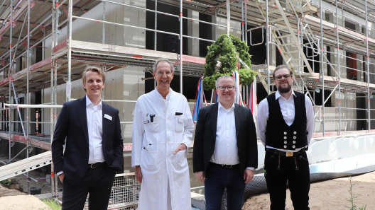 Krankenhausgeschäftsführer, Ärztlicher Direktor, Architekt und Polier stehen beim Richtfest vor dem Neubau des St. Adolf-Stiftes