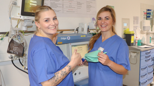 Zwei Pflegerinnen stehen von den medizinischen Geräten in der ZNA und lächeln in die Kamera